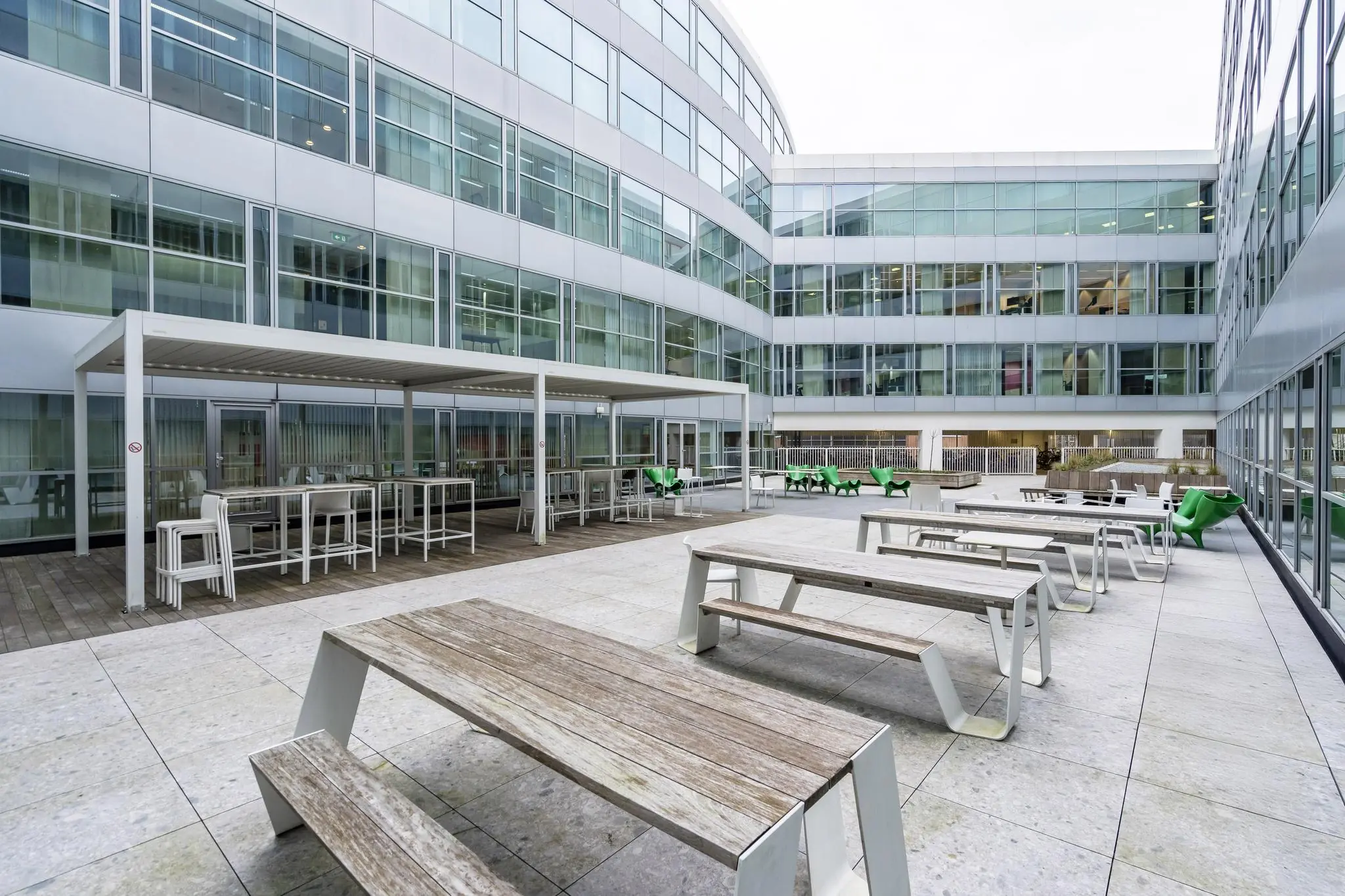 Moderne binnentuin van een kantoorpand aan de Newtonlaan met picknicktafels, overkapping en zitgelegenheden.