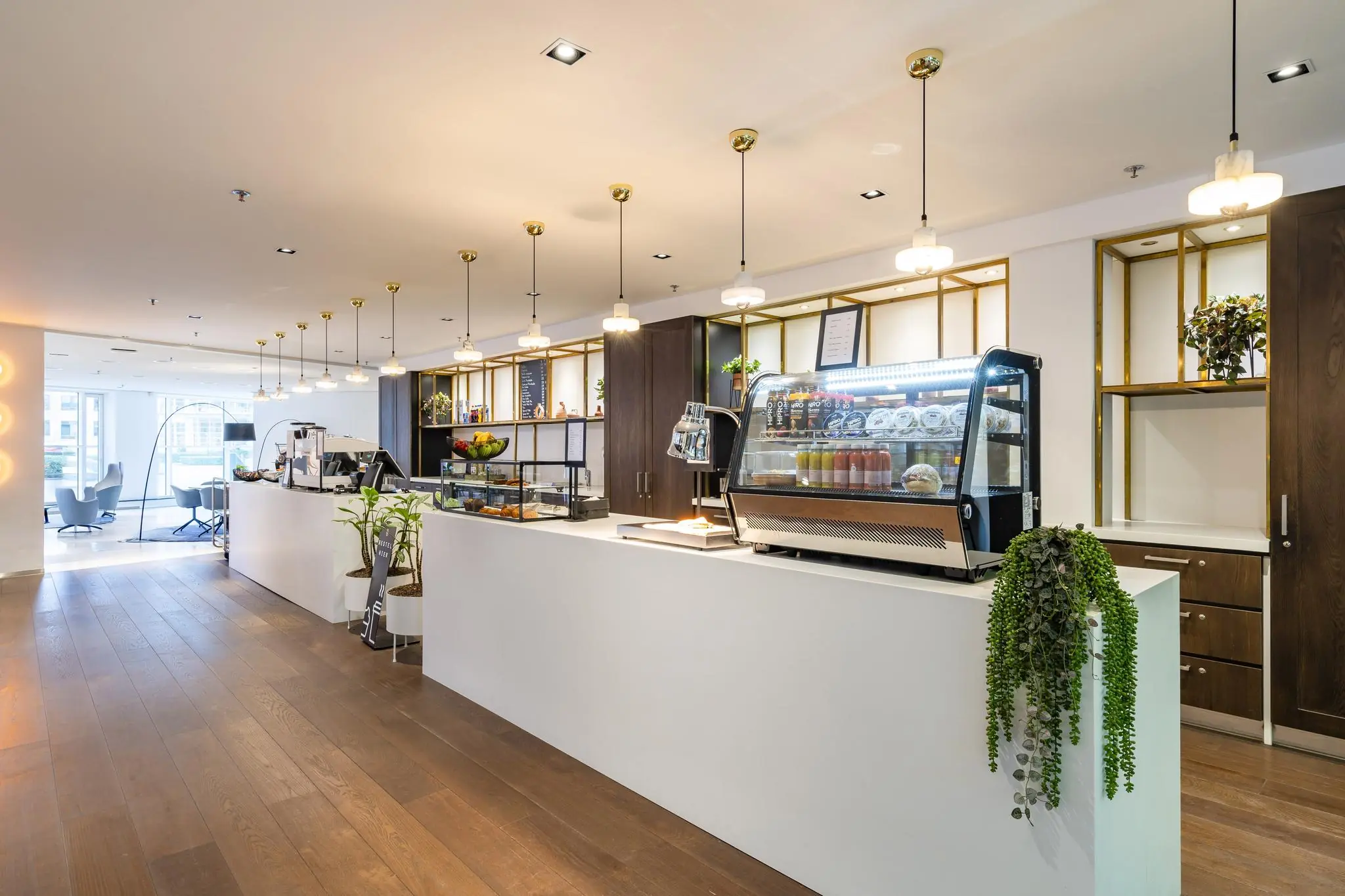 Moderne koffiebar aan de Newtonlaan met een strak interieur, houten vloer en een wit aanrecht met gekoelde vitrine.