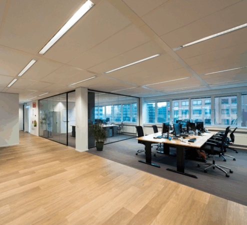 Moderne en ruime kantoorruimte aan de Hogehilweg met werkplekken, glazen vergaderruimtes en uitzicht op omliggende gebouwen.