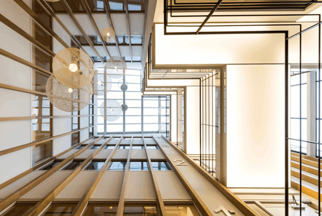 Modern atrium van kantoorgebouw aan de Hogehilweg met houten lamellen, hanglampen en geometrische verlichting.