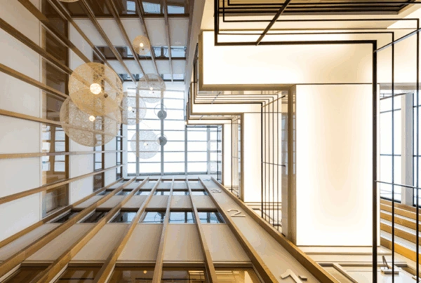 Modern atrium van kantoorgebouw aan de Hogehilweg met houten lamellen, hanglampen en geometrische verlichting.