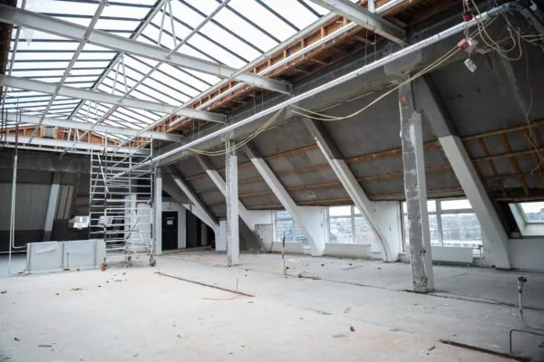 Leegstaande zolderruimte aan het WG-plein in verbouwing met zichtbare dakconstructie en steiger.