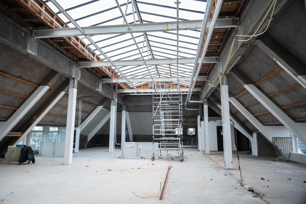 Ruimte onder renovatie op het WG-plein met een open dakconstructie en een steiger in het midden.