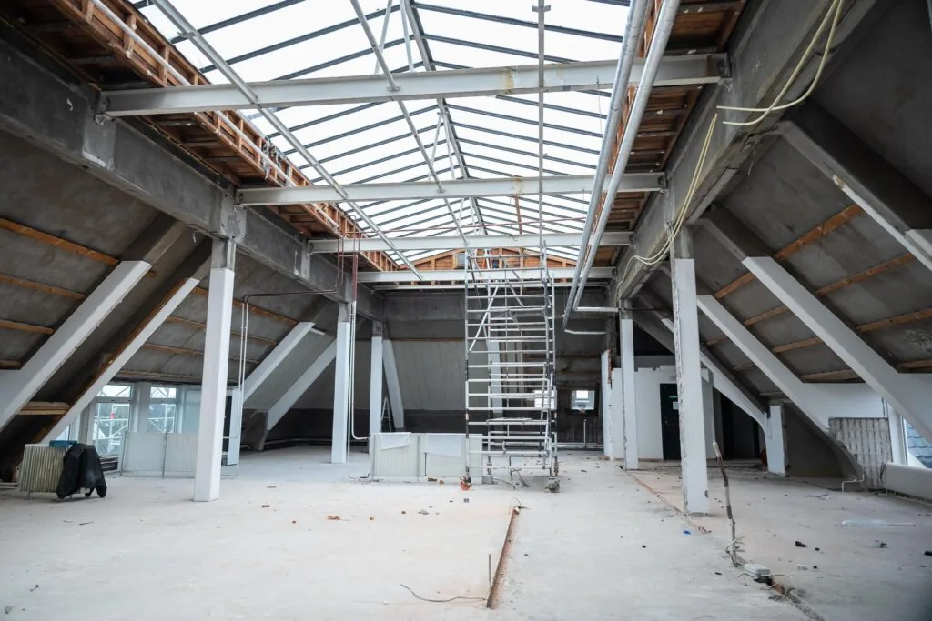 Ruimte onder renovatie op het WG-plein met een open dakconstructie en een steiger in het midden.