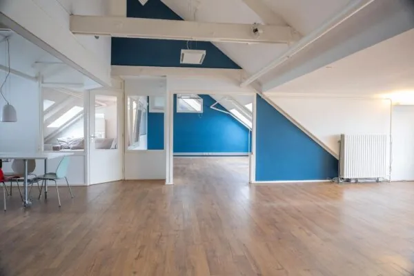 Lichte zolderverdieping met houten vloer, blauwe accentmuren en schuine plafonds op het WG-Plein.