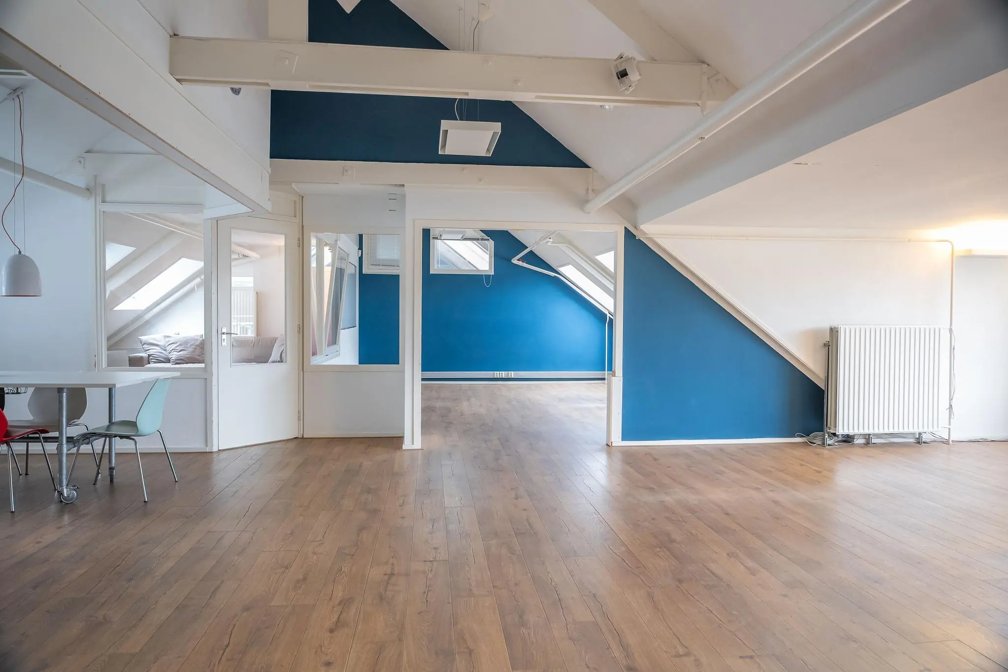 Lichte zolderverdieping met houten vloer, blauwe accentmuren en schuine plafonds op het WG-Plein.