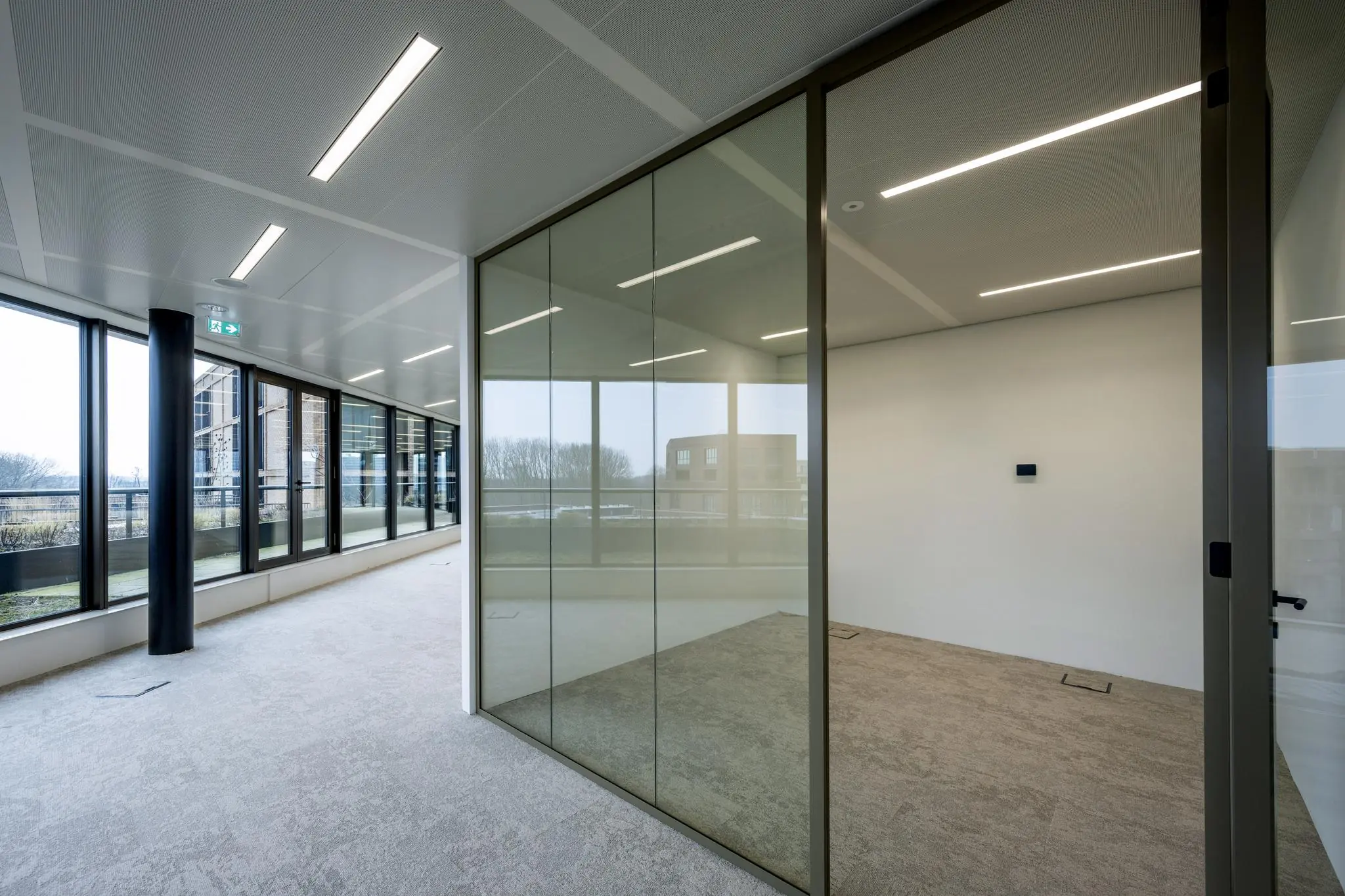 Moderne, lege kantoorruimte aan de Gelrestraat met glazen wanden en uitzicht op een gebouw en bomen.