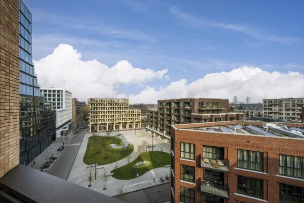 Modern stadsplein aan de Gelrestraat met omliggende appartementsgebouwen en groenvoorzieningen onder een blauwe lucht.