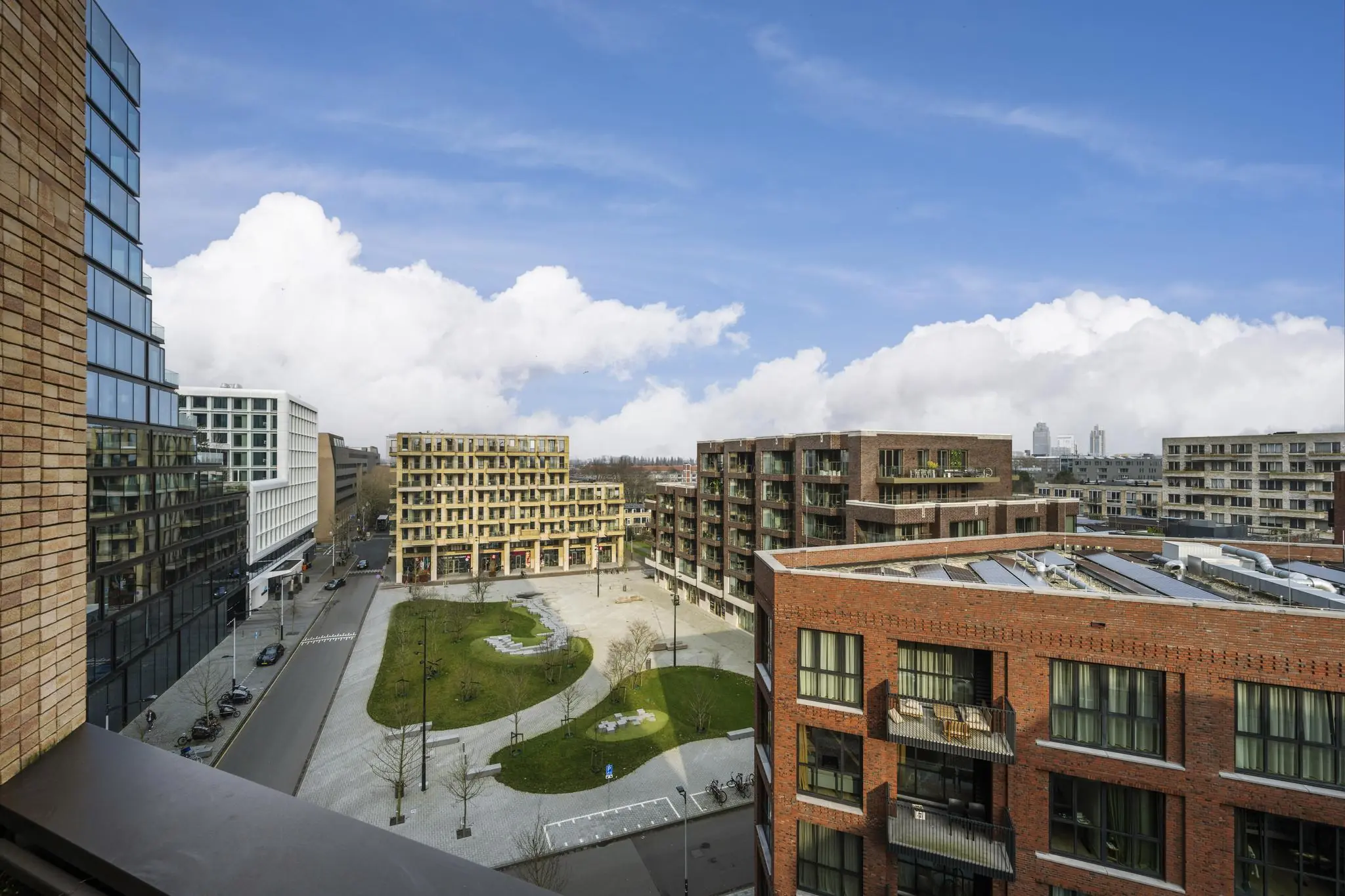 Modern stadsplein aan de Gelrestraat met omliggende appartementsgebouwen en groenvoorzieningen onder een blauwe lucht.