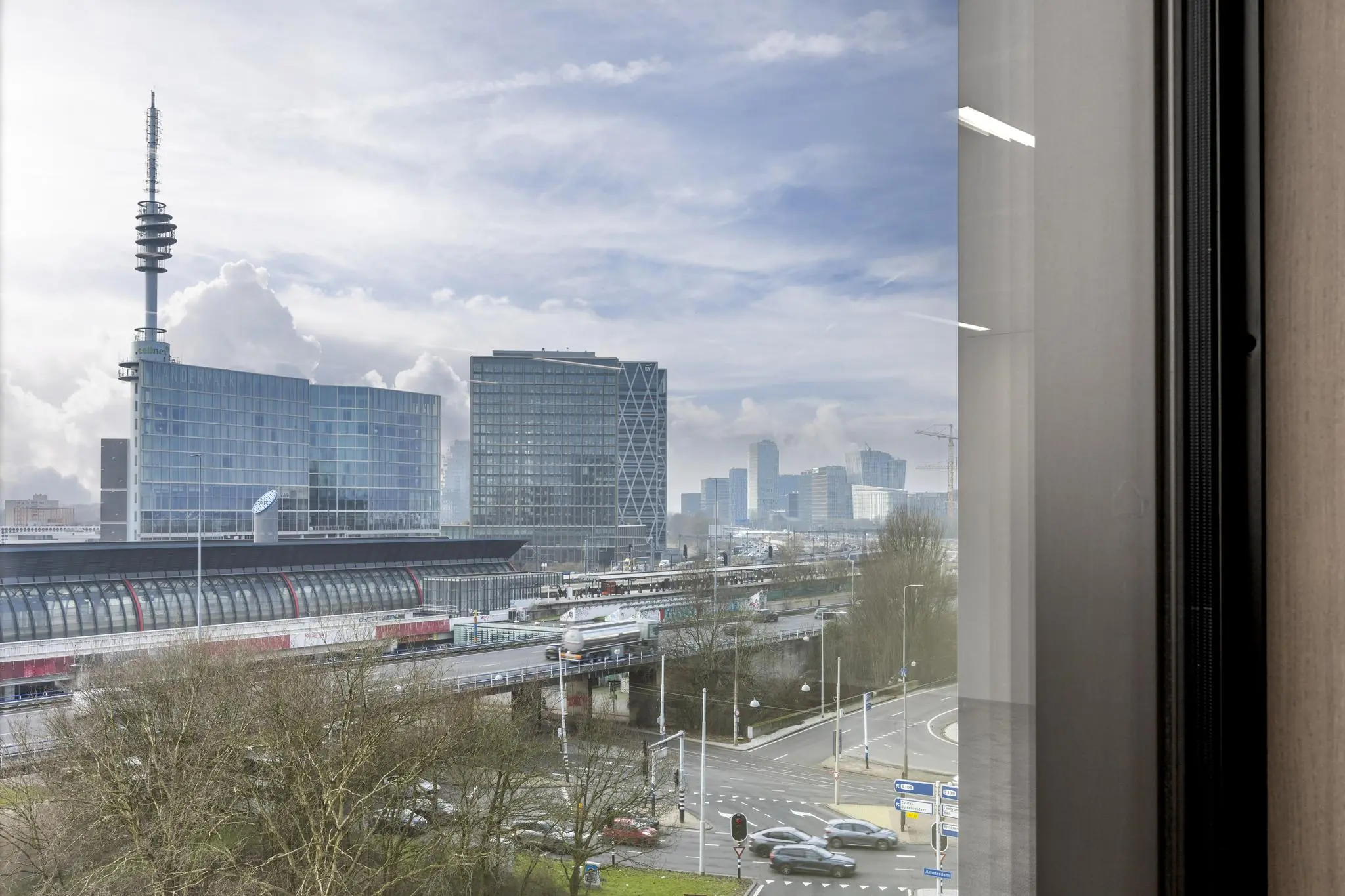 Uitzicht op de Gelrestraat in Amsterdam met moderne kantoorgebouwen, station Amsterdam Zuid en een passerende trein.