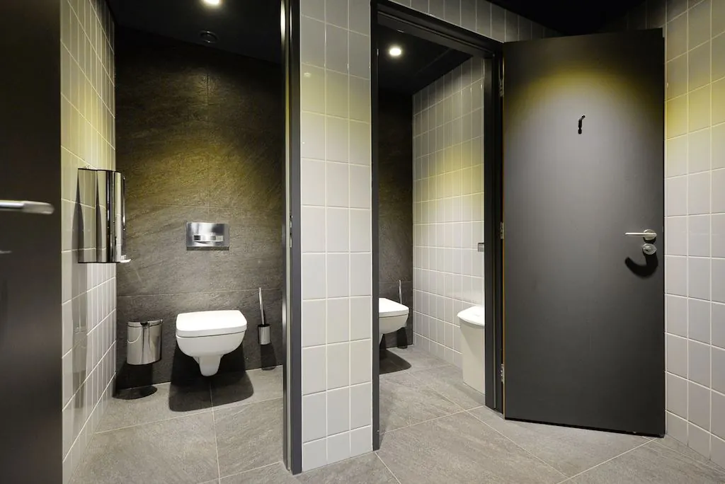 Moderne toiletruimte met twee betegelde toiletcabines en wandclosets in het gebouw aan het Spui.