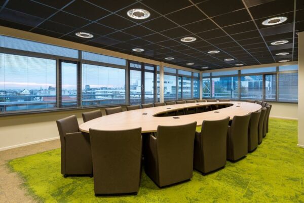 Vergaderruimte met ovale tafel, moderne stoelen en uitzicht op de stad vanaf de bovenverdieping van het gebouw aan het Spui.