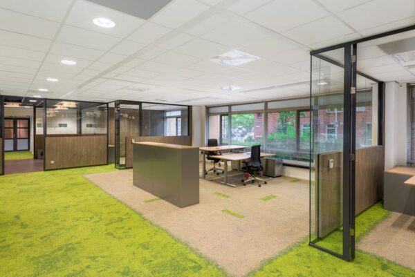 Moderne kantoorruimte aan het Spui met glazen wanden, open werkplekken en groen-beige tapijt.