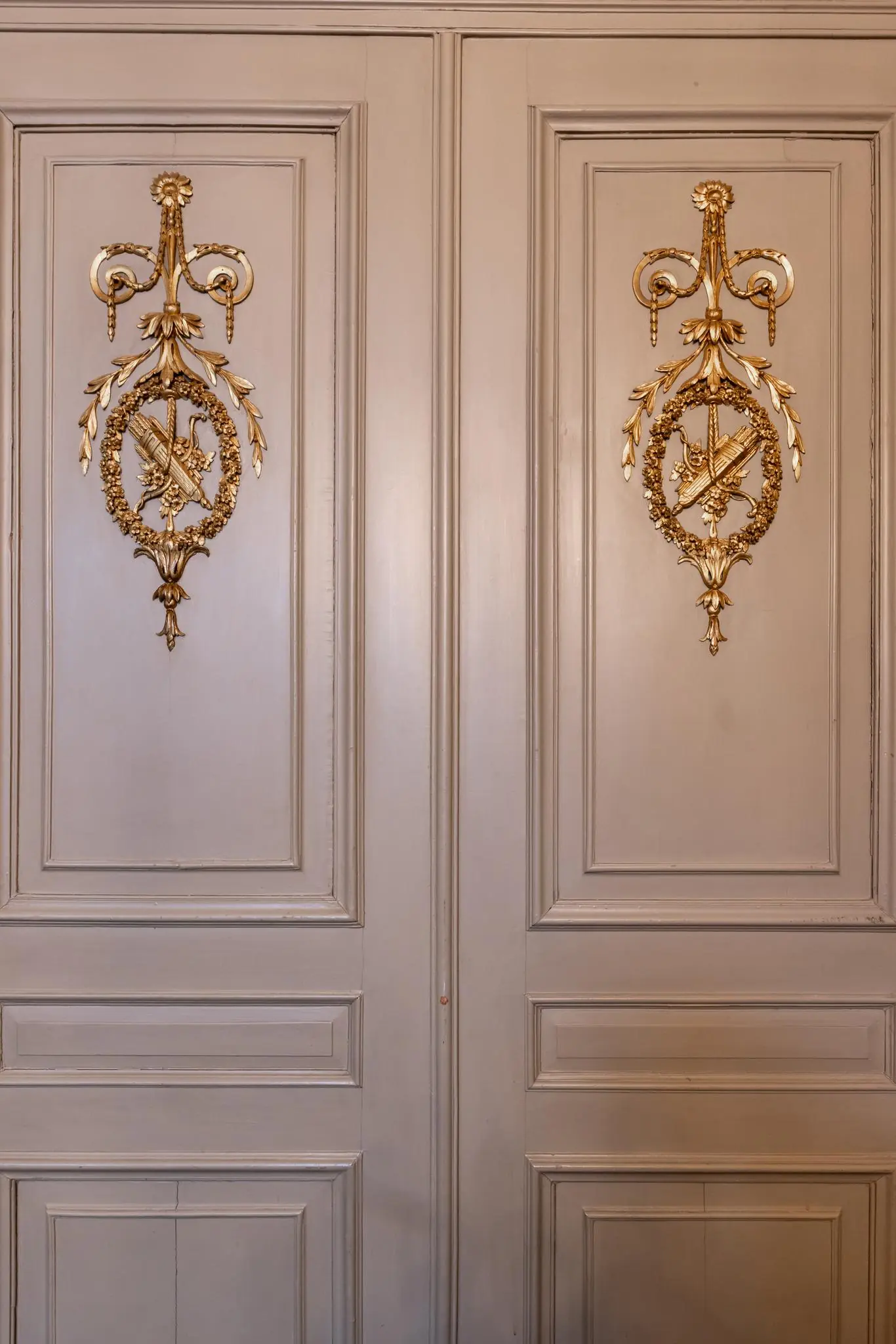 Houten dubbele deur met rijk gedetailleerde, goudkleurige ornamenten in een klassiek interieur aan het Rokin.