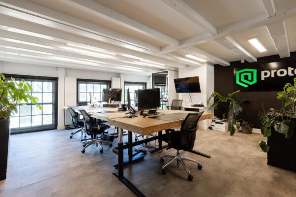 Modern kantoorinterieur aan het Rokin met houten bureaus, ergonomische bureaustoelen, computerschermen en groene planten.
