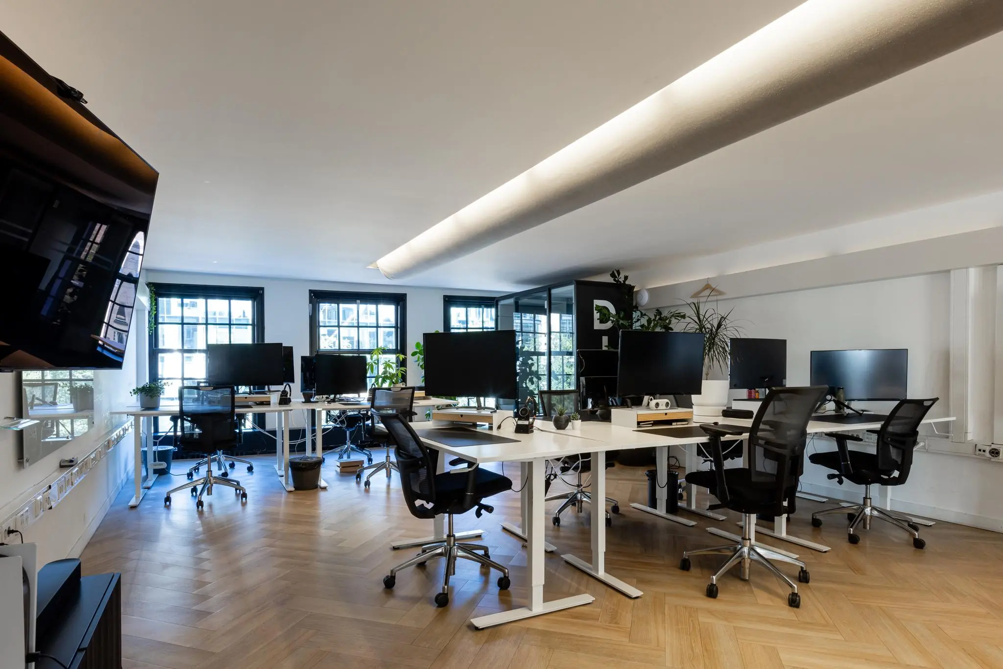 Modern kantoorinterieur aan het Rokin met meerdere werkplekken, ergonomische bureaustoelen en grote ramen voor natuurlijk licht.