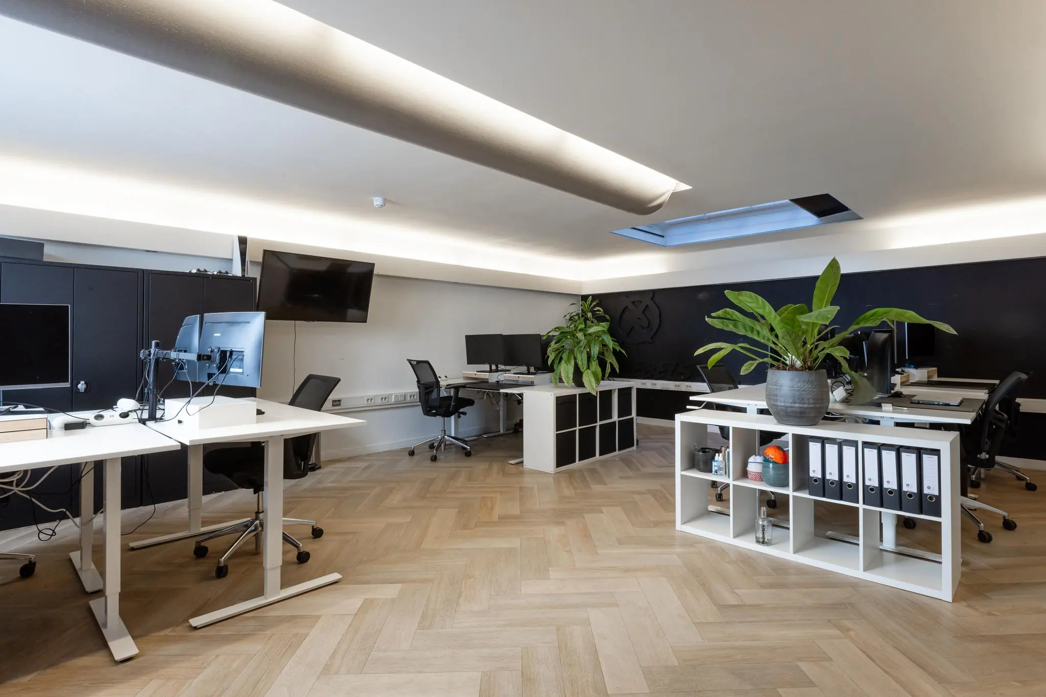 Moderne kantoorruimte aan het Rokin met meerdere werkplekken, planten en een licht houten visgraatvloer.