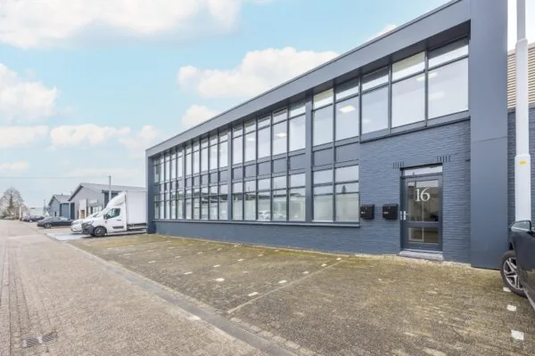 Modern bedrijfspand aan de Industrieweg met grote ramen en parkeergelegenheid voor de deur.