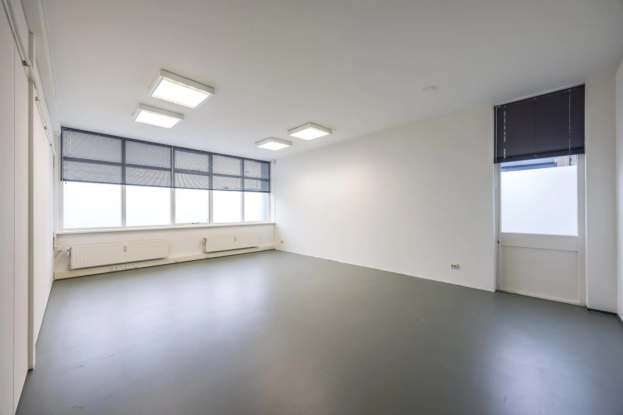 Leeg en strak afgewerkte kantoorruimte aan de Industrieweg met grote ramen en zonwering.