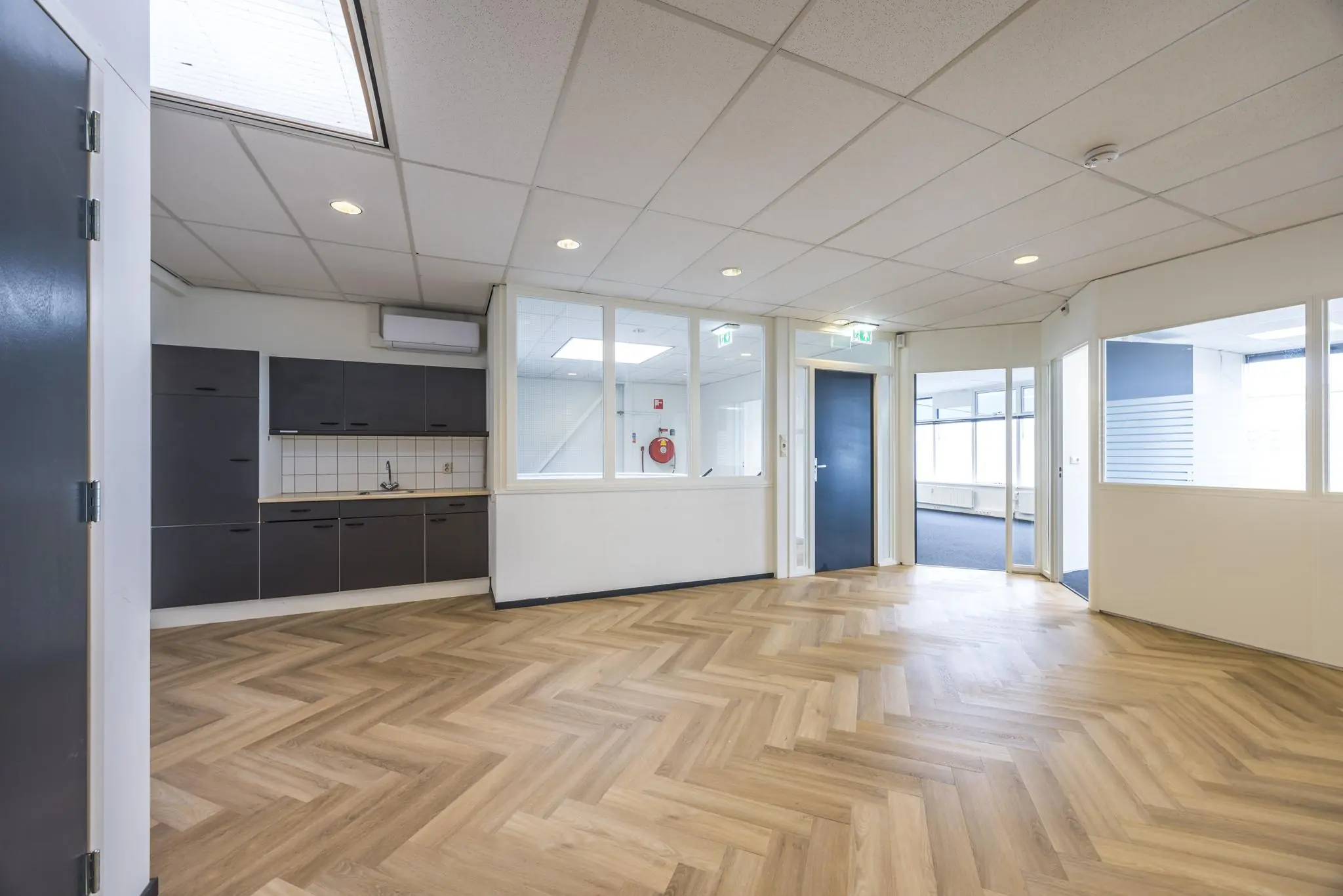 Moderne kantoorruimte aan de Industrieweg met visgraat pvc-vloer, pantry en glazen scheidingswanden.