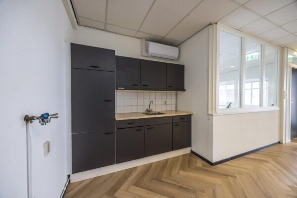 Keukenblok met donkergrijze kasten en een licht werkblad in een kantoorruimte aan de Industrieweg.