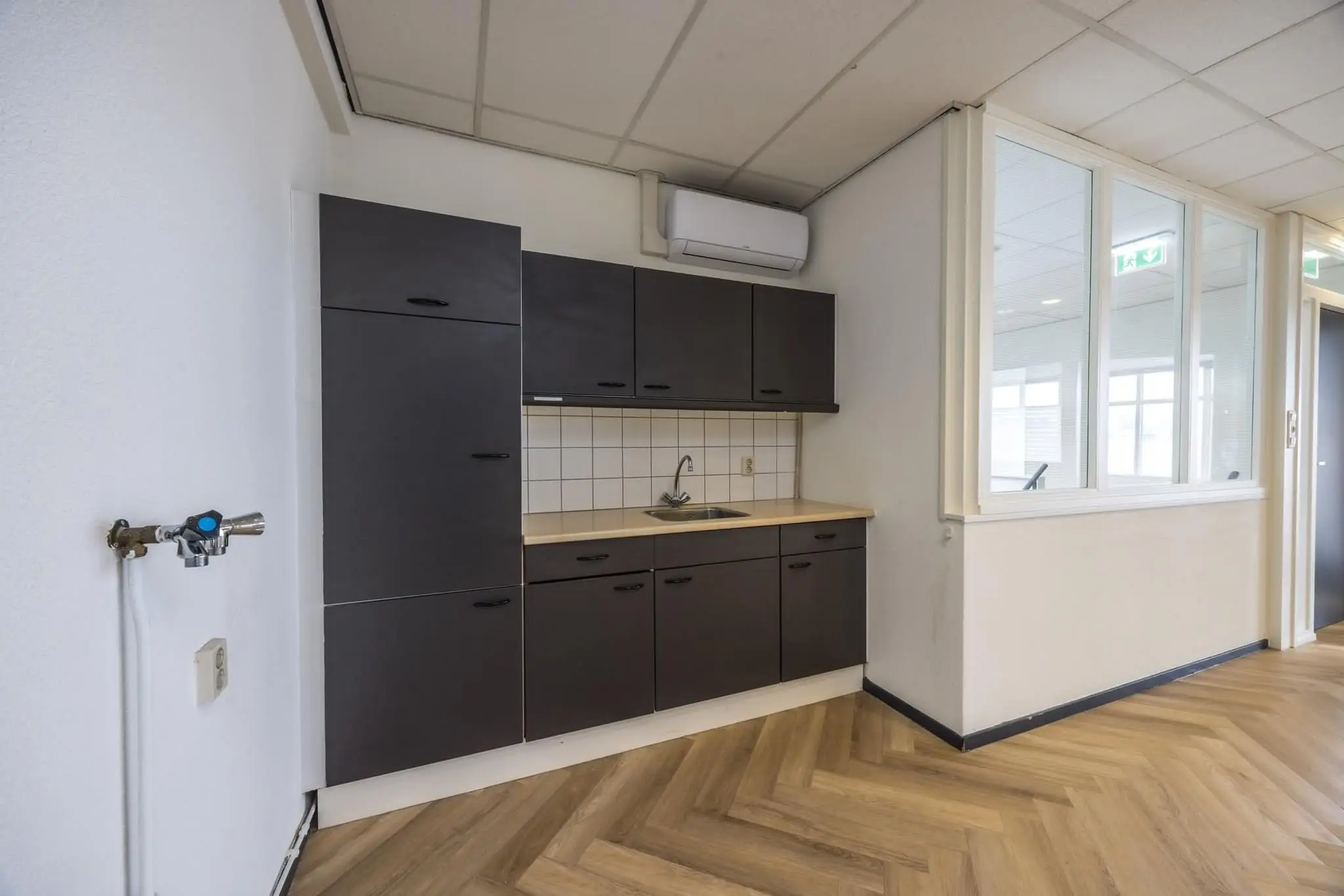 Keukenblok met donkergrijze kasten en een licht werkblad in een kantoorruimte aan de Industrieweg.