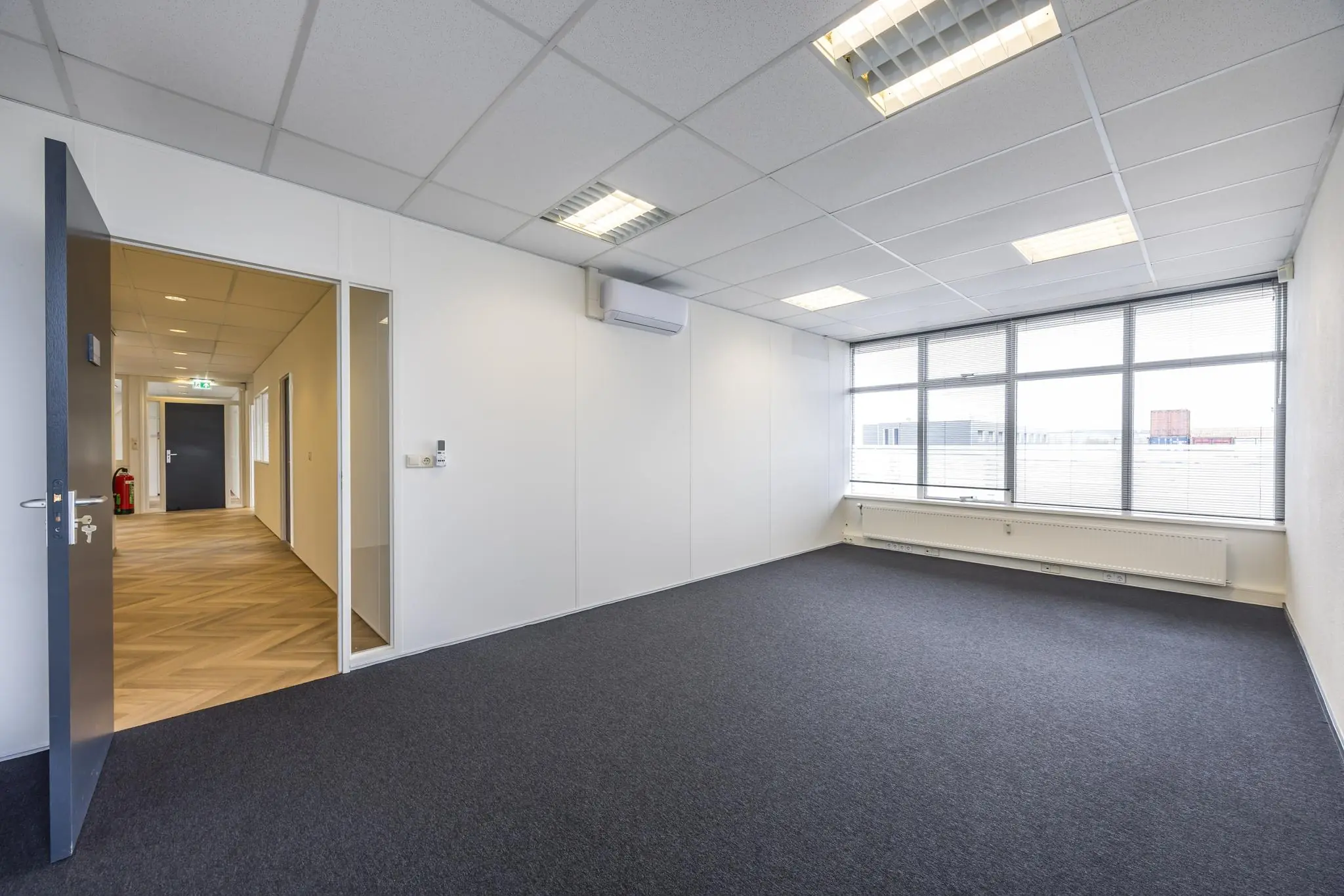 Licht en leeg kantoorruimte aan de Industrieweg met grote ramen en systeemplafond.