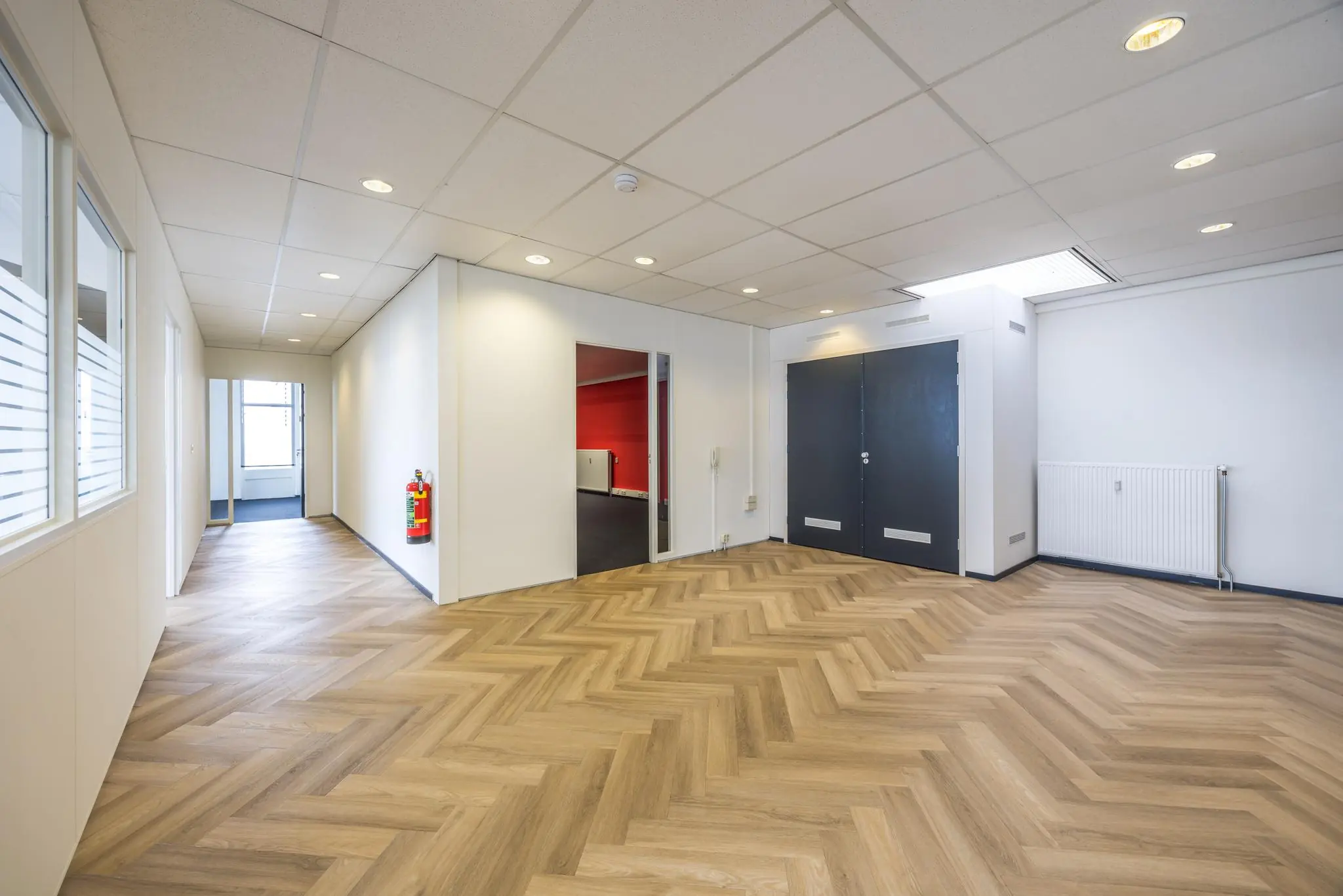 Moderne kantoorruimte aan de Industrieweg met visgraat pvc-vloer, systeemplafond en witte wanden.