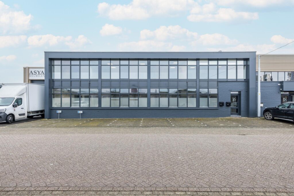 Bedrijfsgebouw aan de Industrieweg met grote glazen gevel, genummerd als pand 16 en met parkeergelegenheid voor de deur.