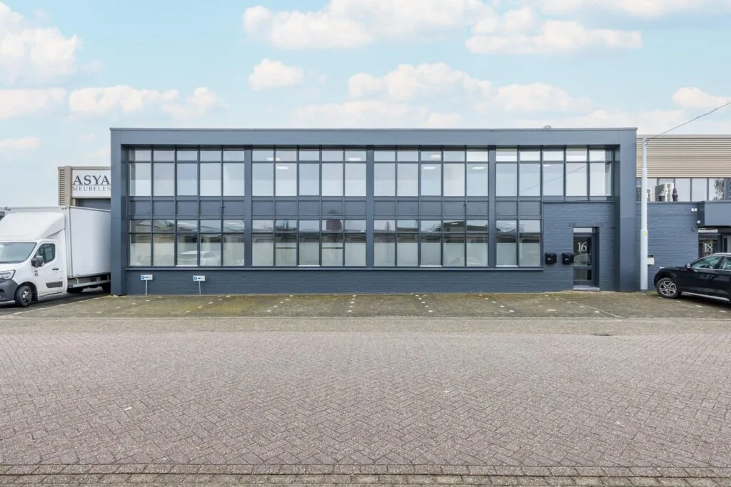 Bedrijfsgebouw aan de Industrieweg met grote glazen gevel, genummerd als pand 16 en met parkeergelegenheid voor de deur.