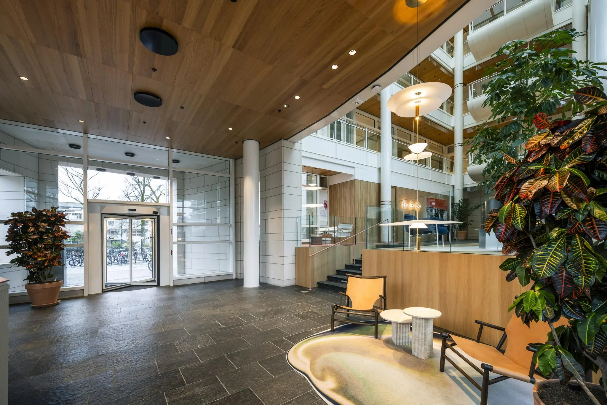Moderne en ruime lobby van een kantoorgebouw aan de Apollolaan met strakke afwerking, veel glas en groen.