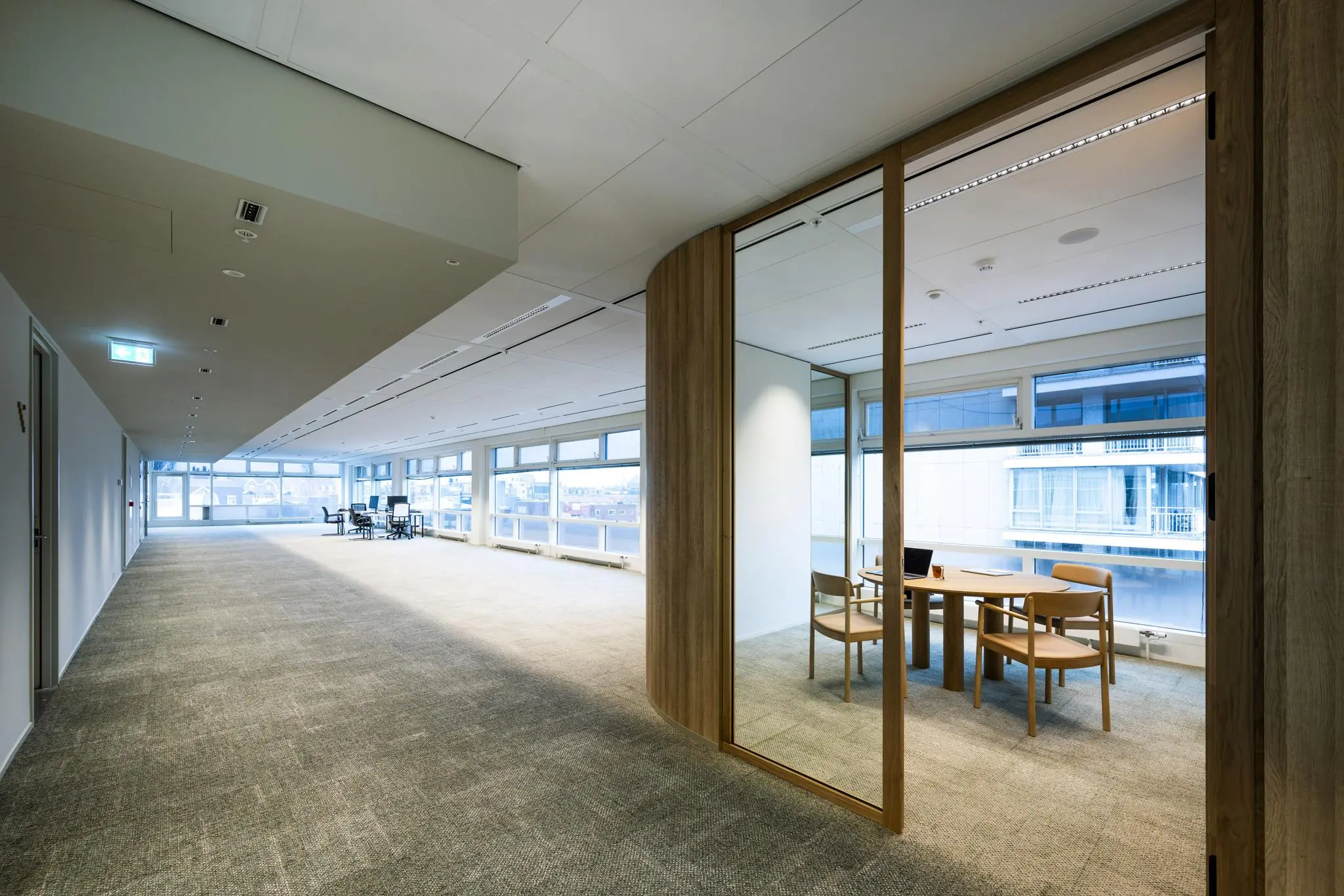 Moderne kantoorruimte aan de Apollolaan met grote ramen, vergadertafel en uitzicht op omliggende gebouwen.