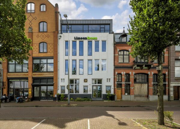 Voorgevel van moderne en historische panden aan de De Ruijterkade in Amsterdam, met het witte kantoorgebouw van LimoenGroen centraal in beeld.