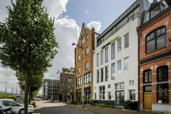 Straatzicht van de De Ruijterkade in Amsterdam met karakteristieke gevels en moderne kantoorpanden.
