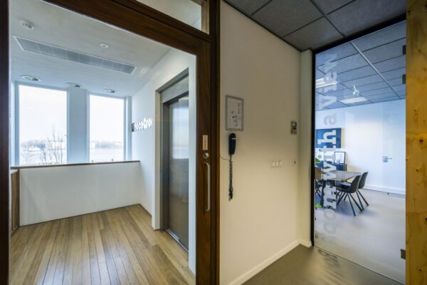Binnenruimte met een glazen deur naar vergaderruimte “room with a view” en uitzicht op het IJ vanaf De Ruijterkade.