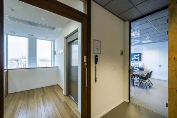 Binnenruimte met een glazen deur naar vergaderruimte “room with a view” en uitzicht op het IJ vanaf De Ruijterkade.