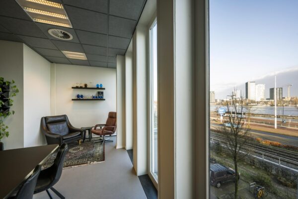 Zitruimte met leren stoelen en uitzicht op het IJ vanaf een kantoor aan de De Ruijterkade in Amsterdam.