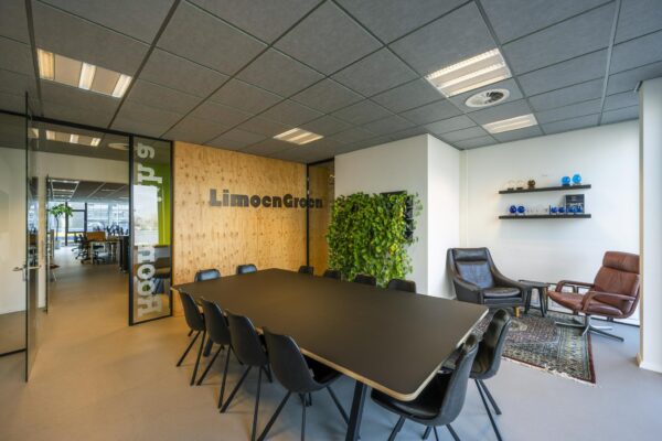 Vergaderruimte van LimoenGroen aan de De Ruijterkade met een grote tafel, moderne stoelen, plantenwand en zithoek.
