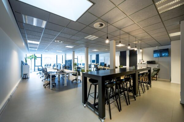Modern en licht kantoorinterieur aan de De Ruijterkade met open werkplekken, hoge tafel en designverlichting.