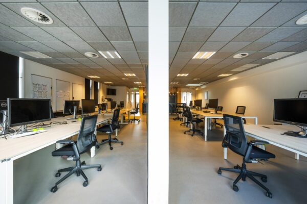 Modern, open kantoorpand aan de De Ruijterkade met meerdere werkplekken en bureaustoelen in een symmetrische opstelling.