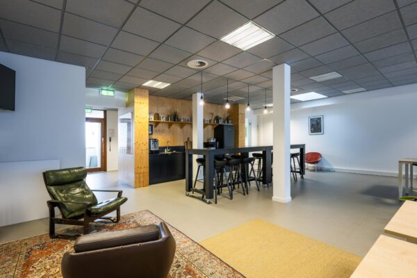 Moderne, open kantoorkeuken aan de De Ruijterkade met zithoek, hoge tafels en houten accenten.