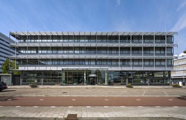 Modern kantoorgebouw aan de Kabelweg in Amsterdam met glazen entree en "Te Huur" borden op de begane grond.