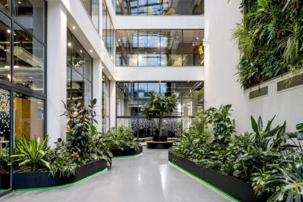 Moderne kantoorhal aan de Kabelweg met grote raampartijen, veel groen en een verticale plantenwand.