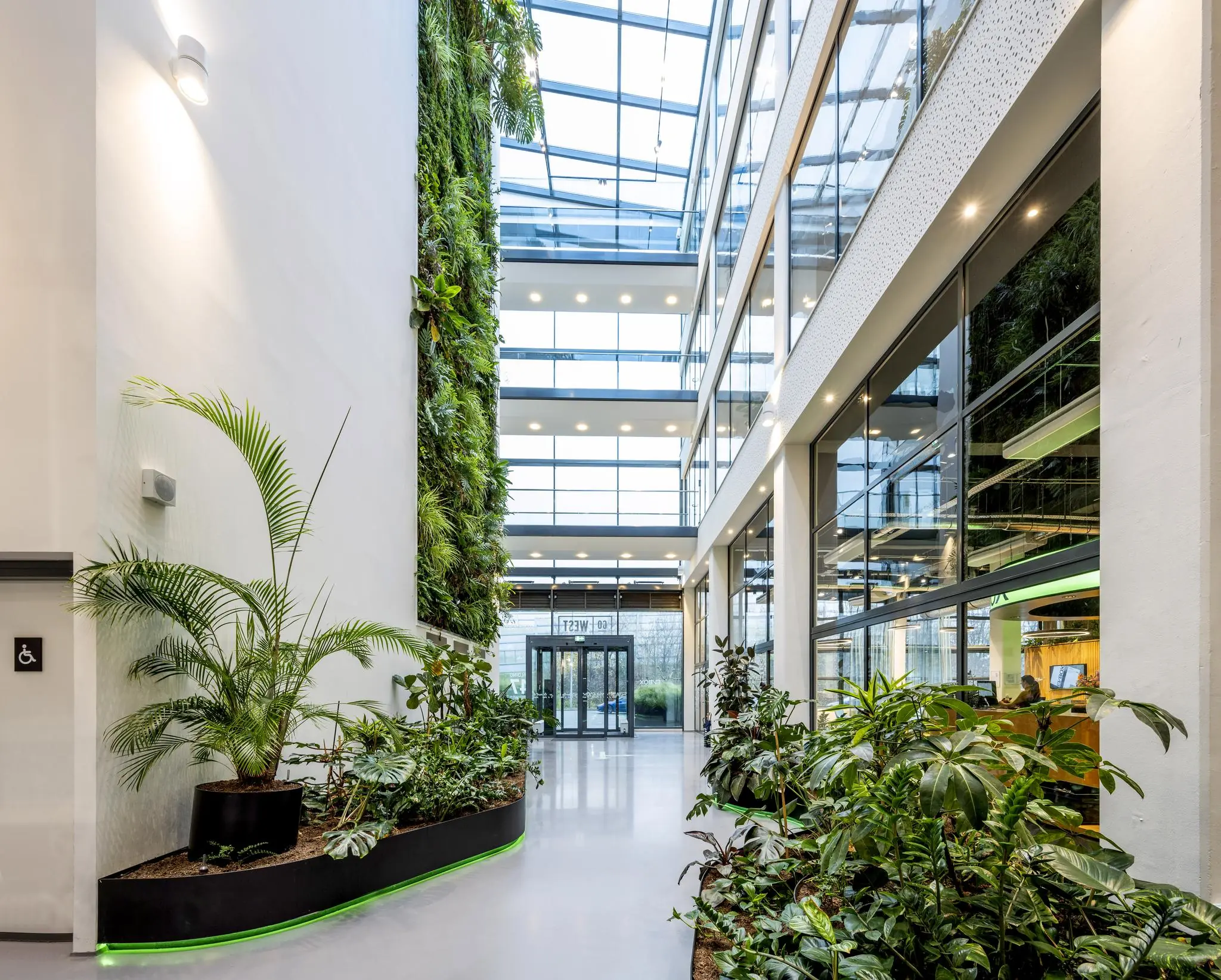 Moderne kantoorlobby aan de Kabelweg met een groene plantenwand en veel daglicht.