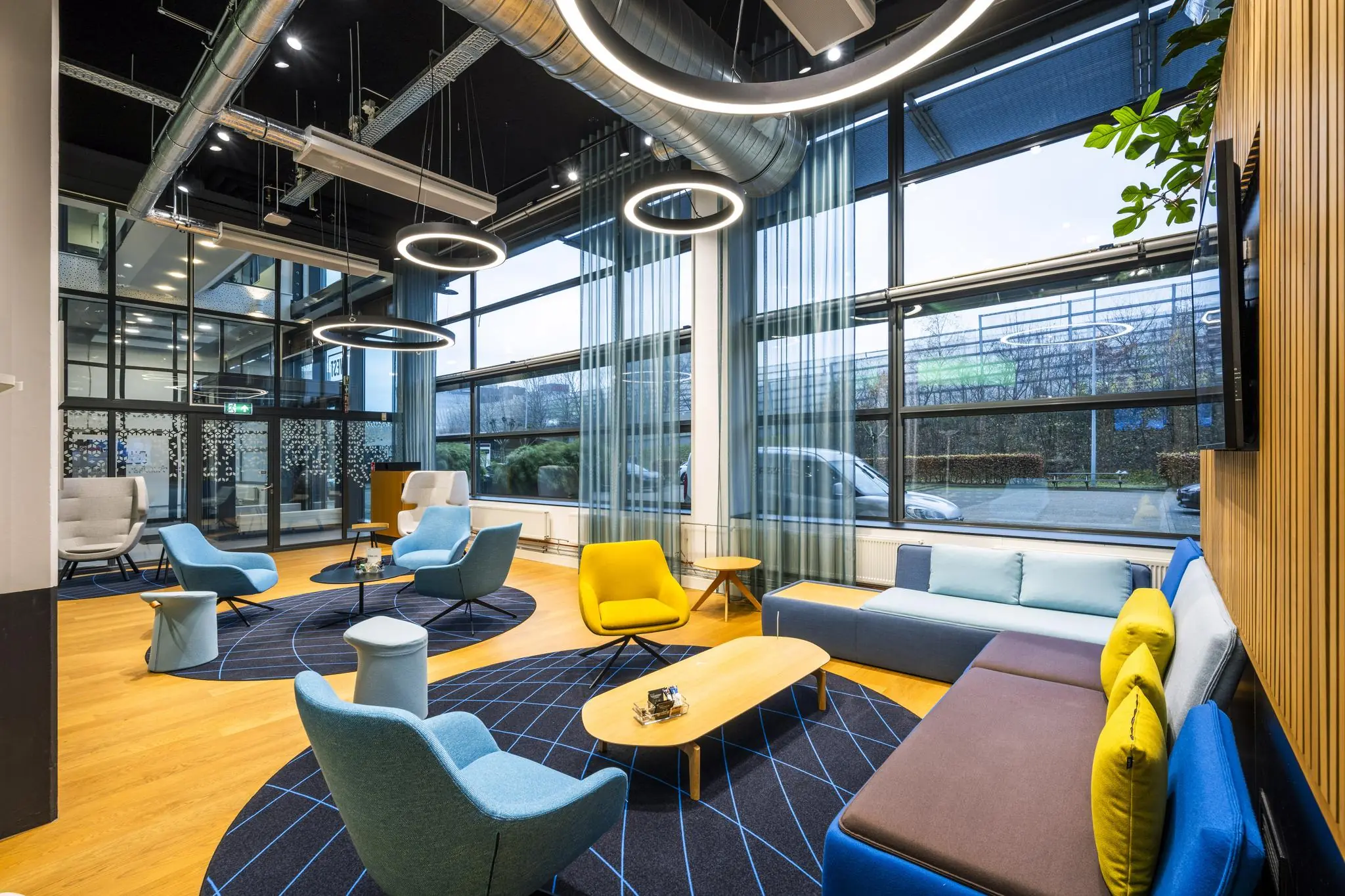 Modern ingerichte wachtruimte met kleurrijke zitmeubels en grote ramen aan de Kabelweg.