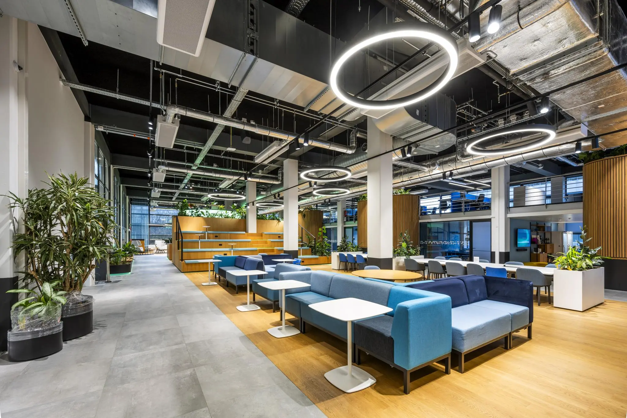 Modern ingerichte kantoorruimte aan de Kabelweg met designmeubilair, planten en opvallende ronde hanglampen.