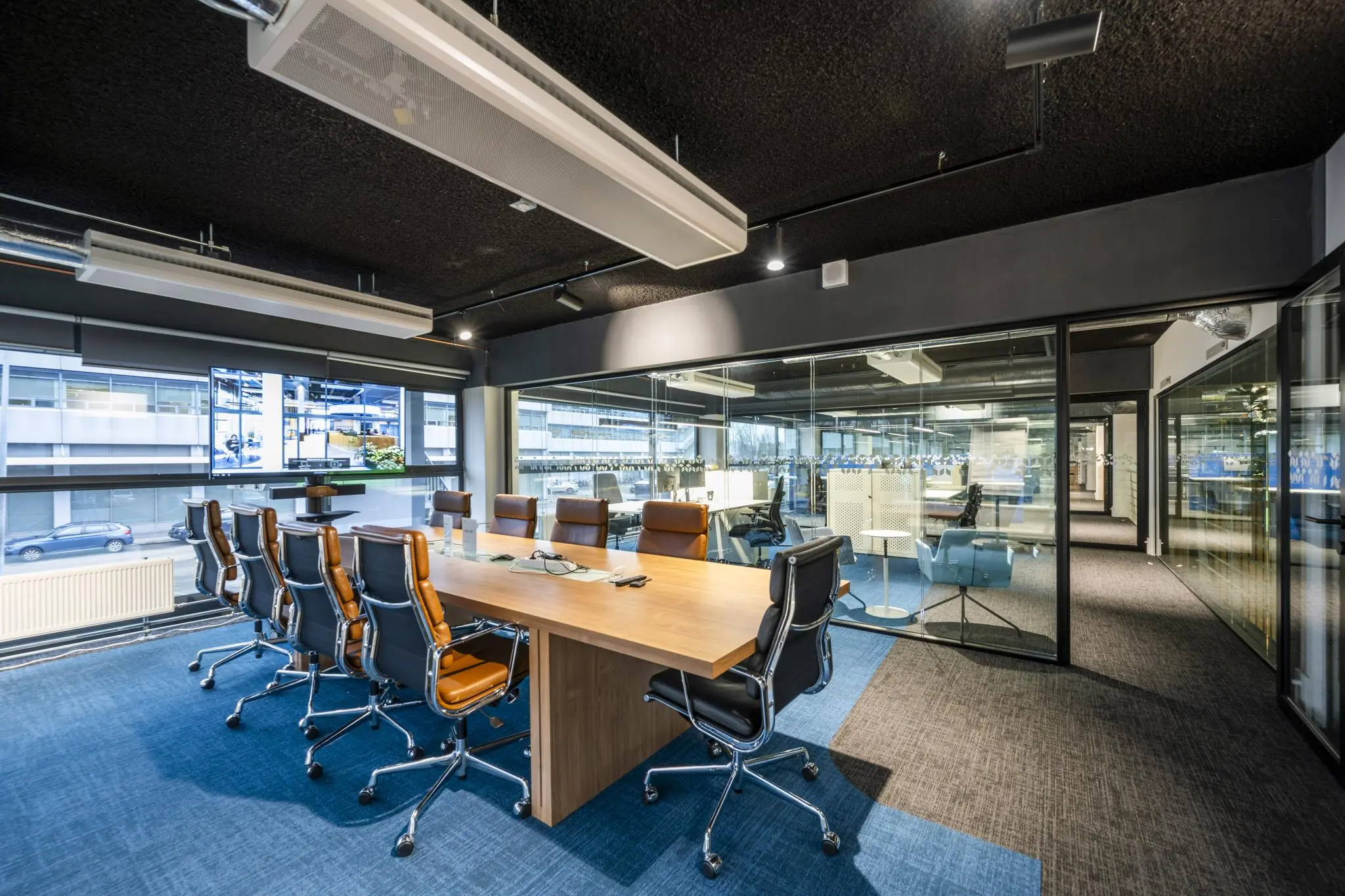 Moderne vergaderruimte aan de Kabelweg met grote houten tafel, leren stoelen en glazen wanden.