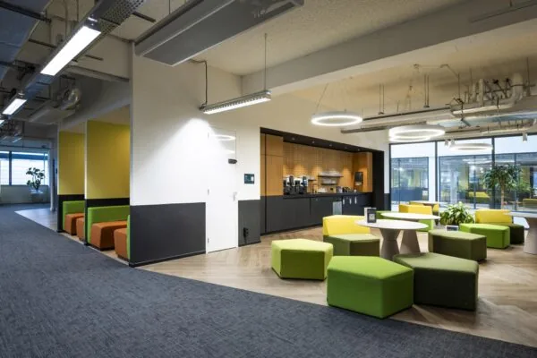 Moderne kantoorruimte aan de Kabelweg met koffiehoek, kleurrijke zitplekken en veel natuurlijk licht.