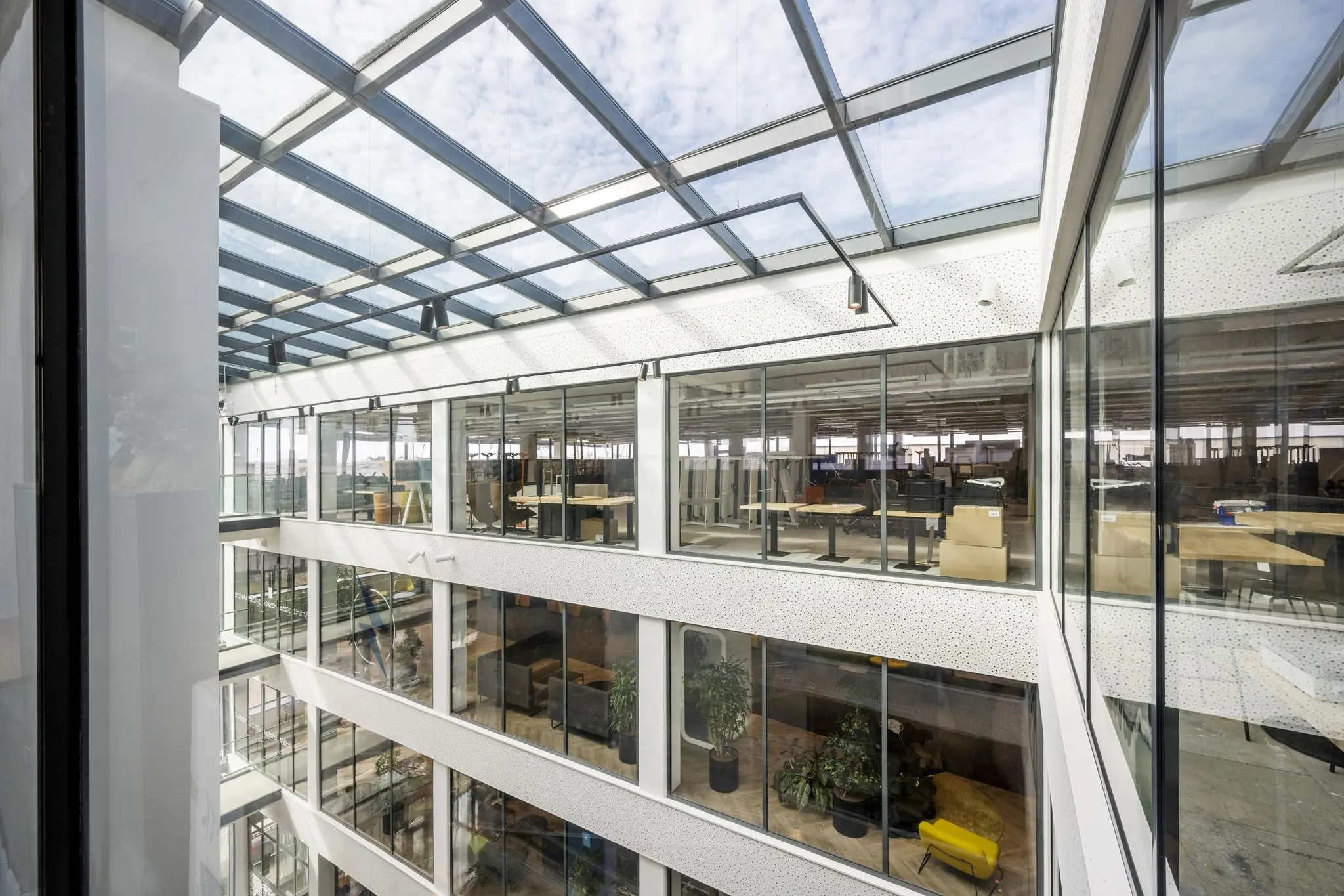 Binnenaanzicht van het moderne kantoorgebouw aan de Kabelweg met glazen dak en meerdere verdiepingen met werkplekken.