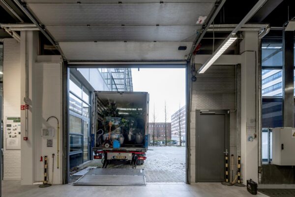 Een vrachtwagen met planten staat uitgeladen in een logistieke ruimte aan de Kabelweg in Amsterdam.